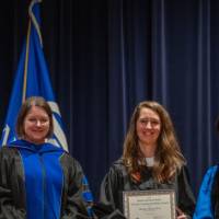 Provost Mili smiles for picture with 2 women on stage